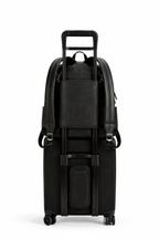 Black suitcase with a backpack style nappy bag on top on a white background