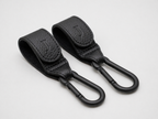 Two black leather Buggy clips with matte black carabiners and an embossed J logo on the front, sitting on a white background 