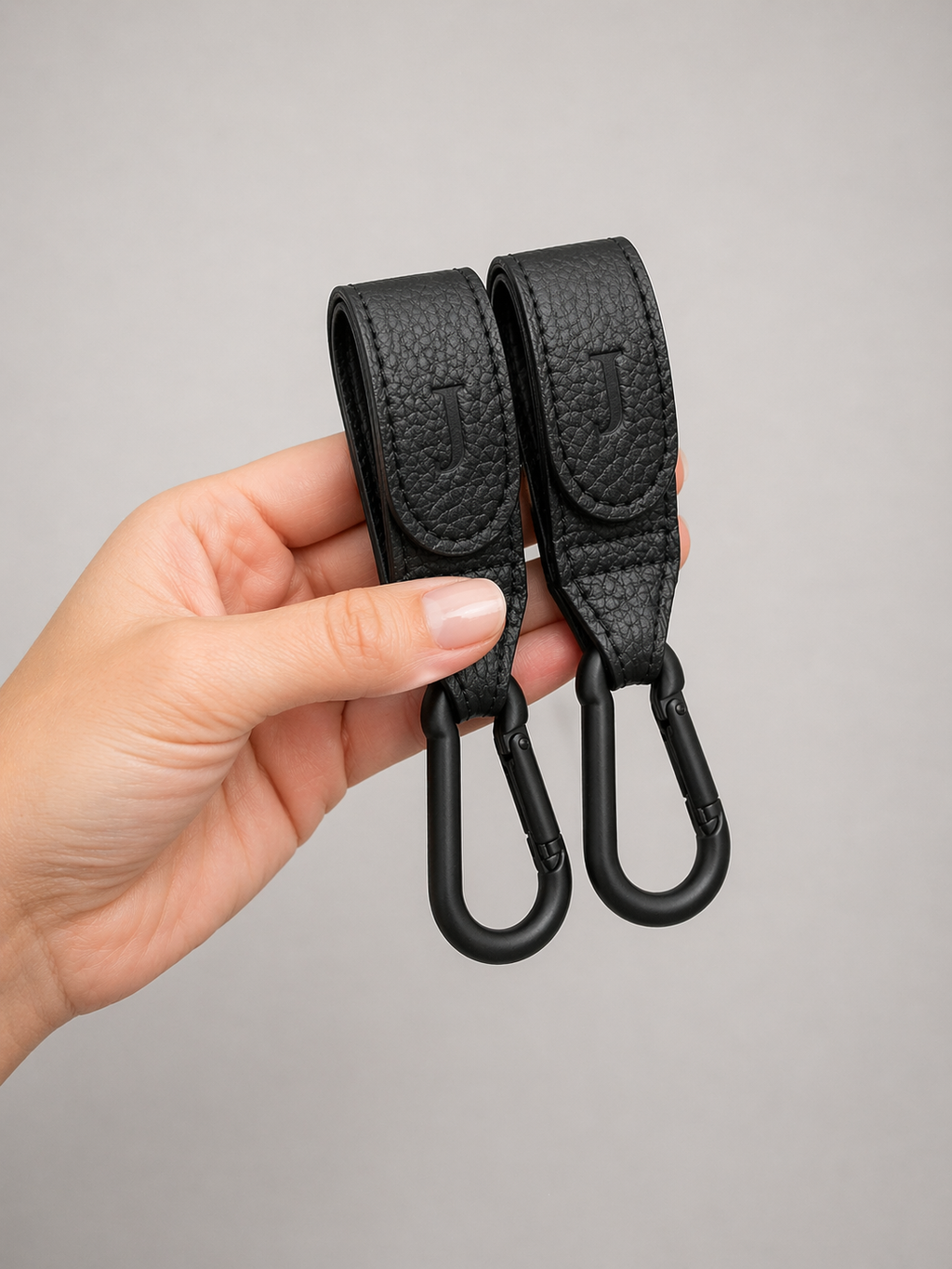 A pair of Josalis the mirror Buggy clips held in a hand to show dimensions on a pale grey background 