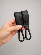 A pair of Josalis the mirror Buggy clips held in a hand to show dimensions on a pale grey background 